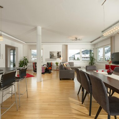 Open-plan kitchen, dining, and living area with large windows.