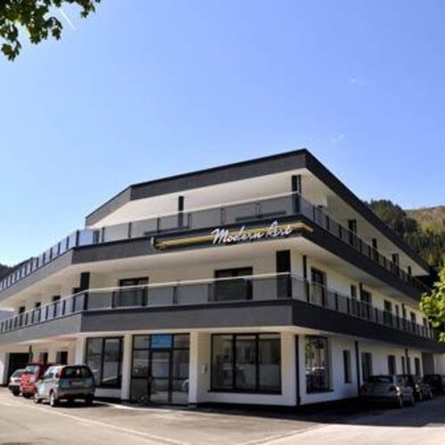 Three-story modern building with balconies and parking.
