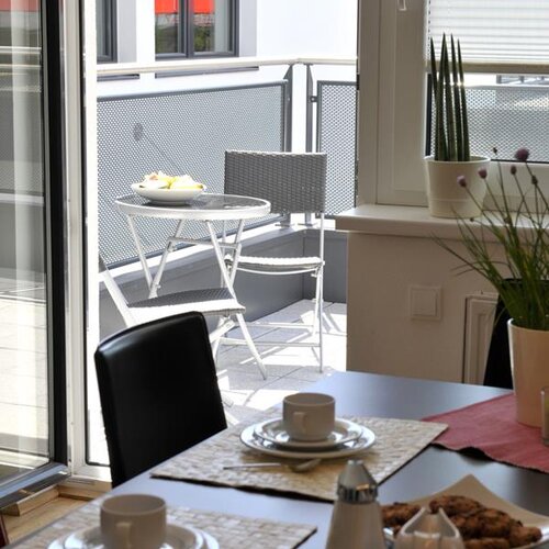 Indoor dining table with two cups and cookies near balcony.