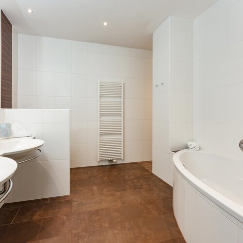Bright modern bathroom with dual sinks and curved tub