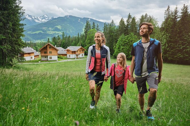 Family of three walking hand in hand across a green meadow