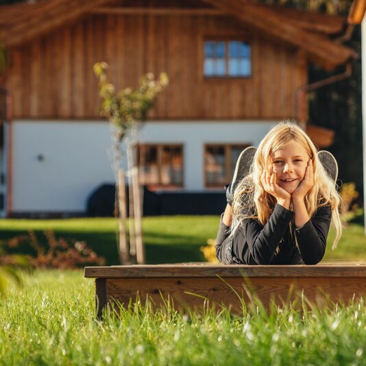 Young girl resting her head on hands outdoors by a wooden house