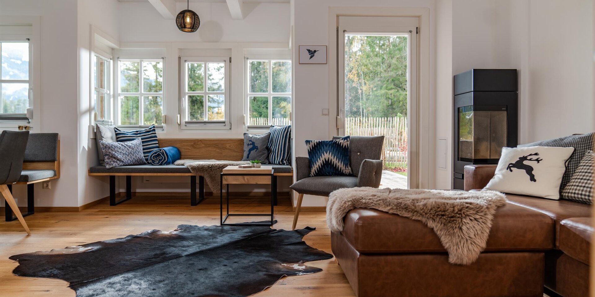 Bright living room with wooden beams, gray seating, and a fireplace.