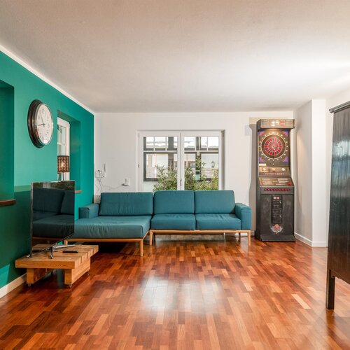 Teal accent wall, teal sofa, and wooden floor living room.