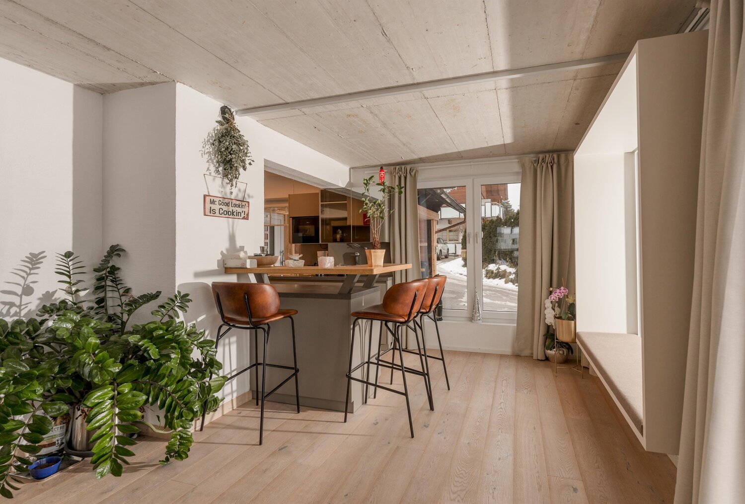 Modern kitchen nook with bar seating and plants.