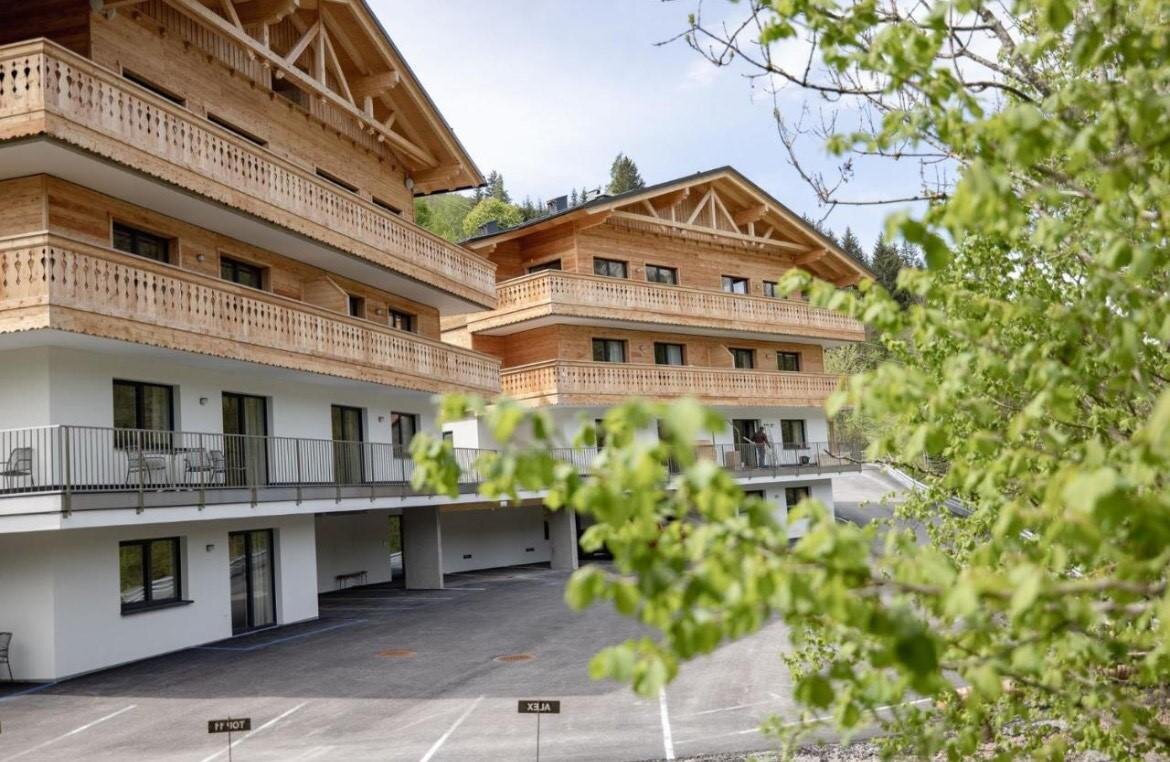 Alpine chalet-style wooden apartment building with multiple balconies
