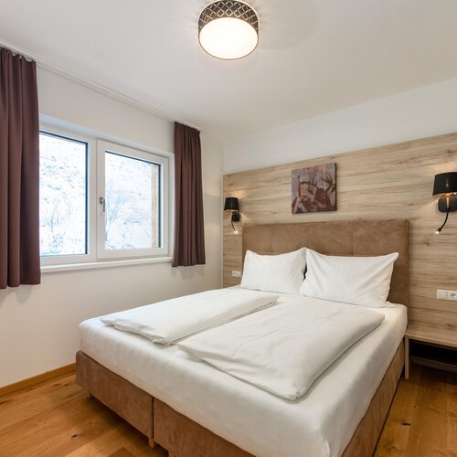 Double bed with white bedding and wooden headboard