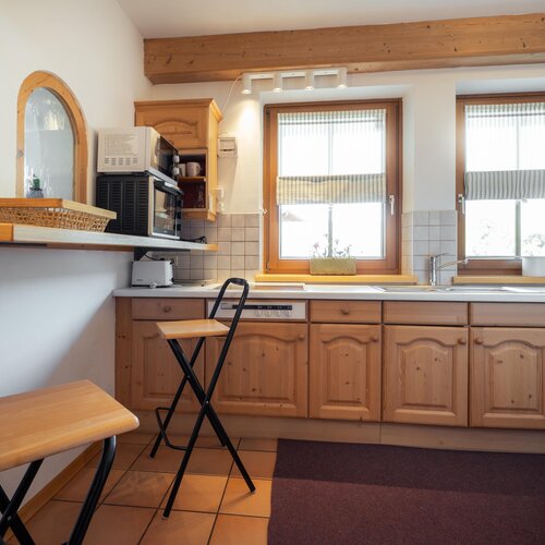 Cozy rustic kitchen with wooden cabinets and two windows | © TIEBER