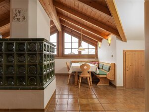 Cozy rustic dining area with wooden beams and tiled stove