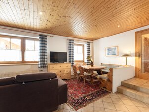 Cozy living and dining area with wooden ceiling and plaid curtains