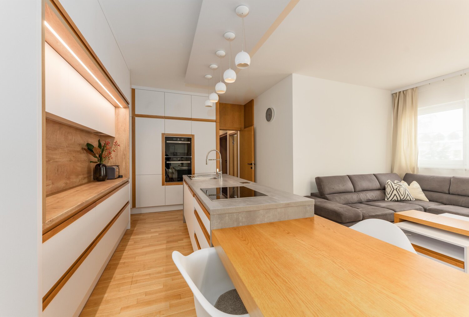 Modern kitchen with island, pendant lights, and living area