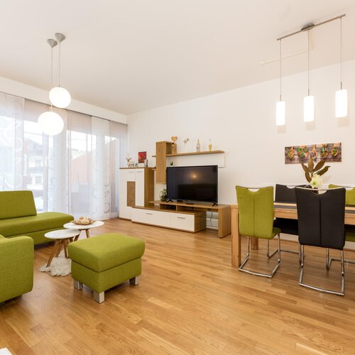 Bright open living room with green sofa and dining area.