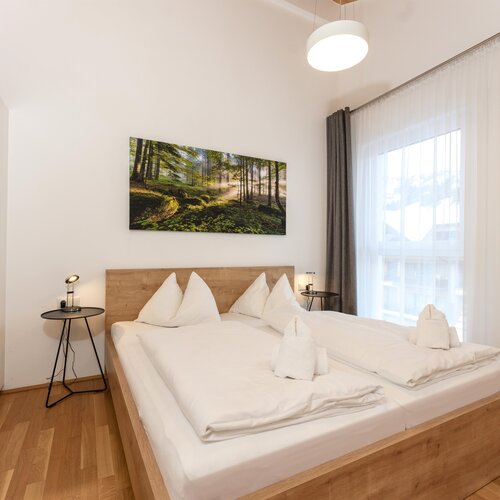 Wooden platform bed with white bedding and forest artwork