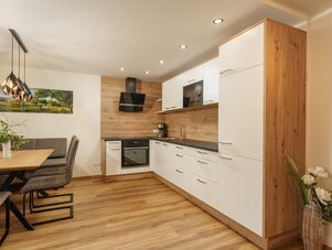 Open-plan kitchen with white cabinets, wood accents, and dining area