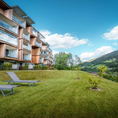 Modern wooden apartment building with balconies on grassy hillside