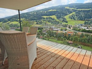 Balcony with wicker chairs overlooking village and hills