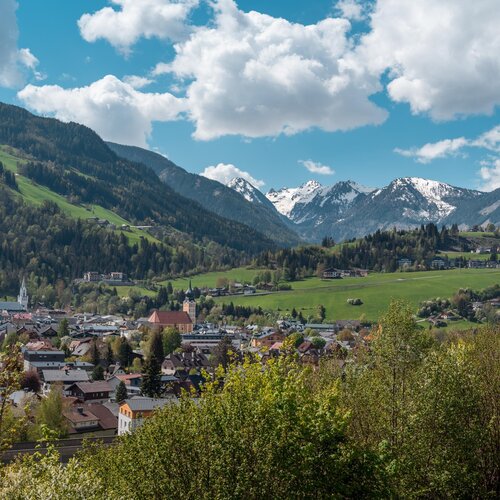 Mountain village in a green valley with snow-capped peaks