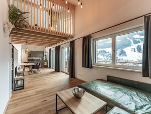 Open-plan living space with couch, dining table, and mezzanine overlooking large windows