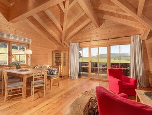 Cozy wooden cabin interior with dining area and red chairs