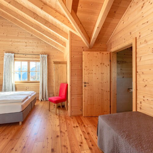 Wood-paneled bedroom with large window and red chair