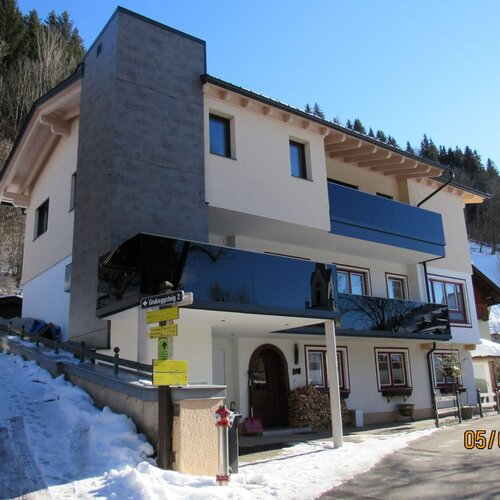 Modern white multi-storey house in snowy hillside setting with glass balcony