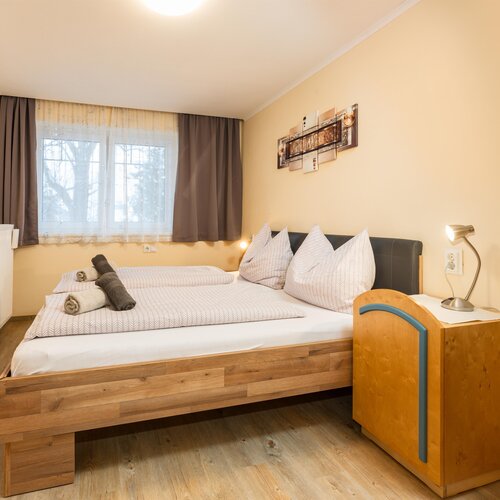 Cozy hotel bedroom with double bed, pillows, and bedside lamp.