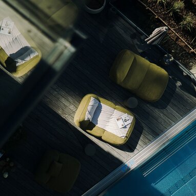 Aerial view of poolside deck with green lounge chairs and magazines