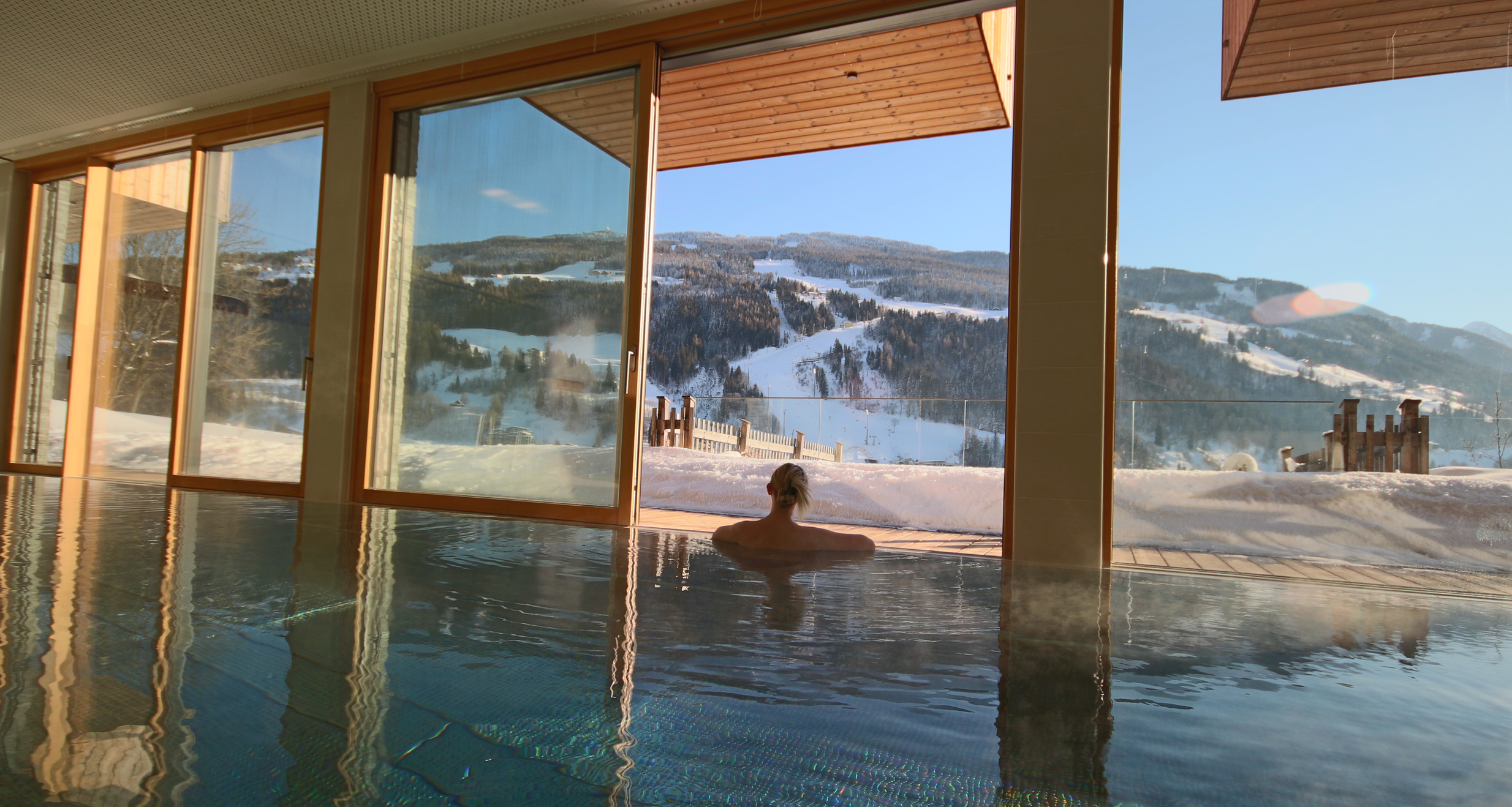 Person swimming in indoor pool with snow scenery outside | © SCHLADMING-APPARTEMENTS